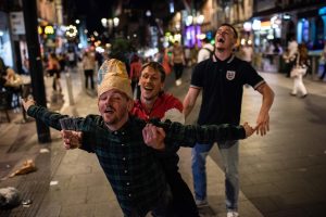 Photograph of three male performers revelling on a high street.